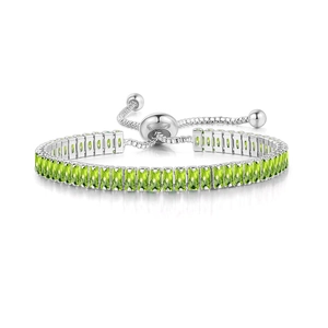 Detailed macro view of silver adjustable tennis bracelet with rectangular green zircons