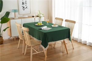 Close-up of dark green cotton tablecloth featuring decorative white tassel fringe details