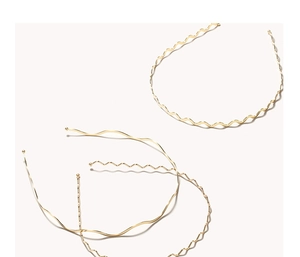 Detailed macro view of three minimalist wavy golden metal headbands with protective tips