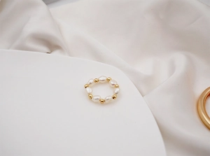 Detailed macro view of baroque freshwater pearl ring with golden beads on silk fabric