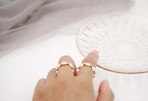 Detailed close-up of Baroque freshwater pearl ring with golden beads on elastic cord