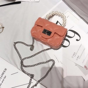 Detail of pink jelly mini bag with diamond quilt pattern and pearl top handle decoration