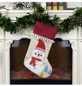 Detail view of burlap Christmas stocking with snowman embroidery hanging on white mantel