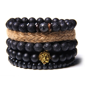 Detail of four-piece natural stone bracelet set featuring lava rock and a golden lion head