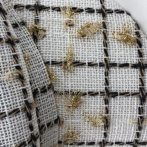 Macro view of tweed fabric texture with gold threads and grid pattern on the newsboy hat