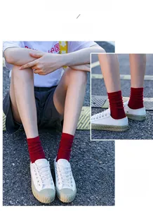 Detail of dark red ribbed knit crew socks paired with white canvas sneakers outdoors