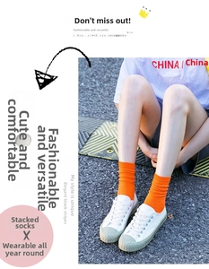 Close-up of orange ribbed cotton slouch socks styled with white canvas sneakers