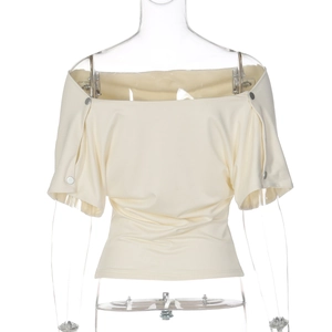 Close-up of cream off-shoulder top featuring silver metal snaps on the sleeves