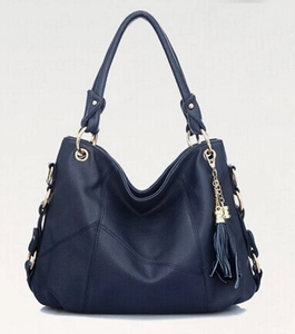 Navy blue soft leather tote bag with tassel charm and gold hardware on light background