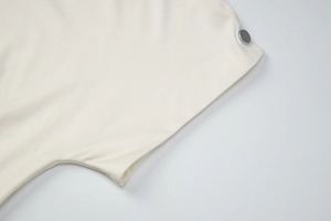 Close-up of cream knit top featuring silver metal button detail and soft fabric texture