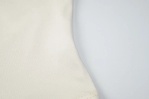 Macro shot of off-white knit fabric showing fine texture and clean bottom hem stitching