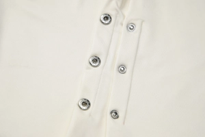 Detail of silver star-engraved metal snap buttons on cream slim-fit short sleeve top