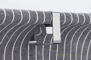 Close-up of a brushed stainless steel U-shaped tablecloth clip securing a striped fabric