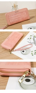 Pink long zip-around wallet with crocodile pattern texture and matching wrist strap detail