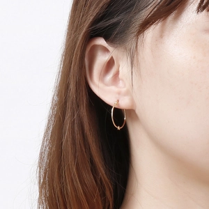 Elegant gold knot hoop earrings in stainless steel on a model with white background