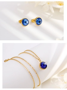 Detail view of gold necklace and stud earrings set with blue round faceted crystals