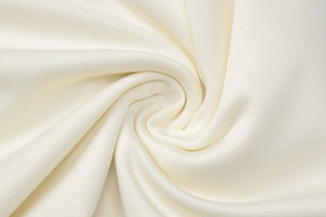 Detailed macro view of cream knit fabric texture with elegant draped folds