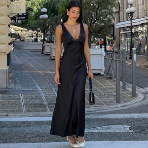 Dettaglio dell'abito lungo in raso nero con bordo in pizzo raffinato sullo scollo a V