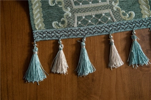 Close-up of dark green jacquard table runner with high-density silver grey fringe tassels