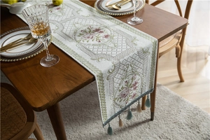Close-up of beige chenille table runner with floral jacquard and delicate fringe tassels