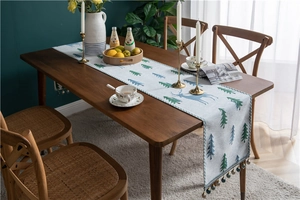 Detail of blue reindeer chenille table runner featuring decorative tassels on wooden table