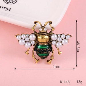 Detail of bee brooch with pearls, green enamel, and black crystals in antique gold finish