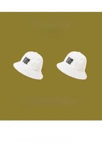 Vue détaillée de bobs en coton blanc avec impression de lettres SYAM EIDE noires sur le devant