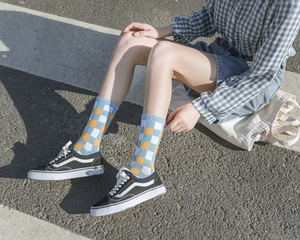 Close-up of blue and yellow checkerboard cotton socks worn outdoors on pavement