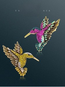 Macro detail of hummingbirds brooch with colorful rhinestones on vintage alloy