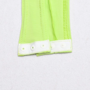 Detail view of fluorescent green bodysuit showing white plastic snap buttons and ribbed fabric