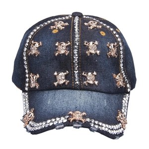 Detail of blue denim baseball cap featuring golden metal skulls and silver rivets