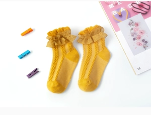 Detailed view of yellow children's lace socks with mesh design on white background