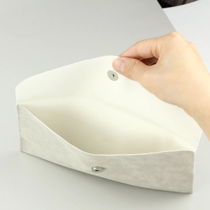Macro view of light grey suede envelope bag showing magnetic snap closure and interior