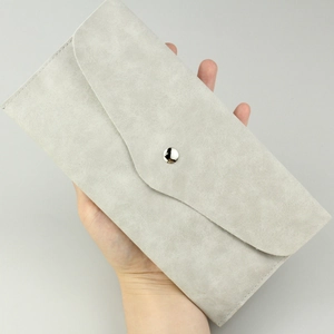 Detail of light gray faux suede makeup brush pouch featuring an envelope flap and snap button