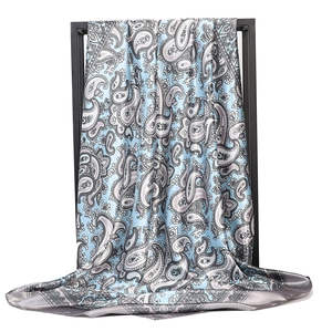 Detail view of large paisley print satin scarf featuring light blue and grey elegant texture