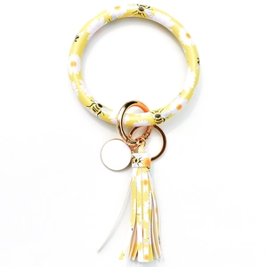Detailed view of yellow floral bee pattern leather tassel keychain bracelet with gold ring
