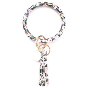 Close-up of black floral print PU leather bracelet keyring with long golden tassel