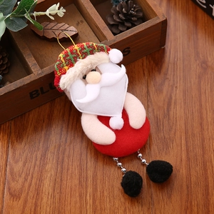 Dettaglio di Babbo Natale in peluche con cappello a maglia e gambe di catena su tavolo in legno