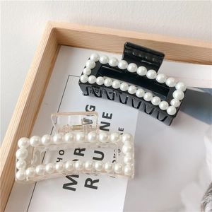 Detail of square hair claws with white pearls in black and transparent colors