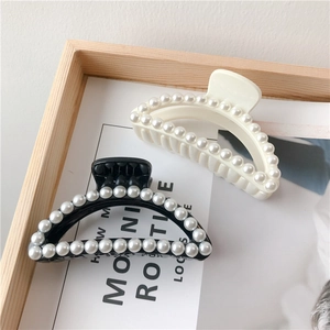 Detail view of elegant semi-circular hair claws with white pearls in black and white
