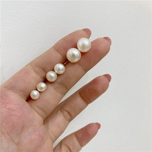 Detailed scale comparison of various sizes of natural white freshwater pearls held by hand