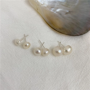 Detailed macro shot of three sizes of natural freshwater pearl earrings on white fabric