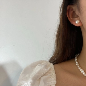 Model wearing natural freshwater pearl stud earrings and a matching round pearl necklace