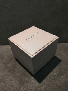 Macro view of square pink textured jewelry gift box with silver silk-printed logo on lid