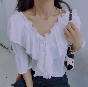 Close-up of a white off-shoulder top featuring layered ruffles and soft draped pleats