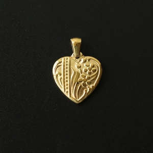 Detailed close-up of a 18K gold-plated heart pendant with floral relief on black background