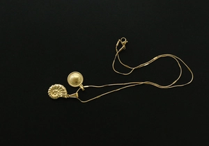Detail of 18K gold-plated shell and round pendants on a vintage minimalist chain