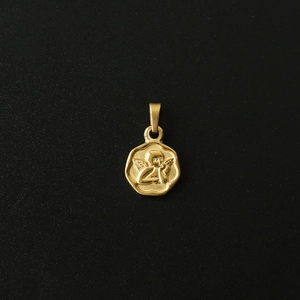 Macro shot of 18K gold plated stainless steel cherub coin pendant with embossed detail