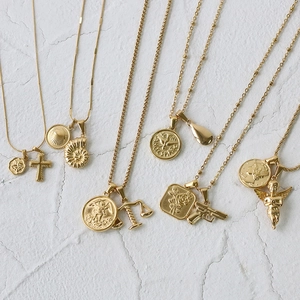 Flat lay of multiple 18K gold-plated stainless steel coin and cross pendant necklaces