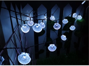 Cold white LED shell string lights glowing on a garden fence for outdoor decor